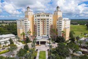 Stunning hotel with a central entrance, flanked by two towers, set amidst beautifully manicured lawns and palm trees.
