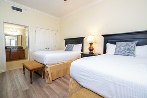 Two single beds with matching headboards and footboards, each with a pillow, are set against a light-colored wall.