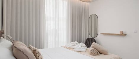Cama bem arrumada com toalhas, espelho na mesinha de cabeceira e prateleira de madeira.
