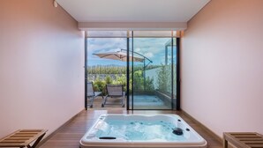 A hot tub in a room with a sliding glass door leading to an outdoor patio with a table and chairs.