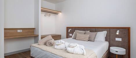 A modern bedroom with a large bed, bedside tables, a hanging light fixture, and a built-in shelf.