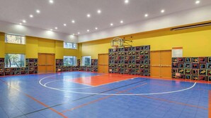 A basketball court with a blue and orange floor, surrounded by yellow walls and windows. - Hilton Vacation Club Palm Canyon (Palm Springs)