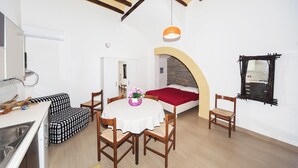 A compact room with a bed, a dining table with chairs, a kitchen area, and a small bathroom. - Visitsicilia Donn'Anna 1 (Castellammare del Golfo)