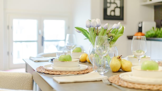 A dining table set with plates, glasses, and fruits, with a vase of flowers and a framed picture on the wall. - Cecilia House in Lucca (Lucca)