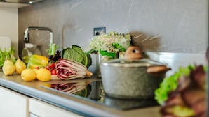 A kitchen counter with fresh produce, a pot, and a vase of flowers. - Cecilia House in Lucca (Lucca)