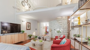 A modern living room with a flat-screen TV, red and blue sofas, a coffee table, and a decorative shelf. - Cecilia House in Lucca (Lucca)