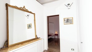 A room with a large mirror, patterned floor tiles, a wooden bench, and a door leading to another room. - Visitsicilia Donn'Anna 2 (Castellammare del Golfo)