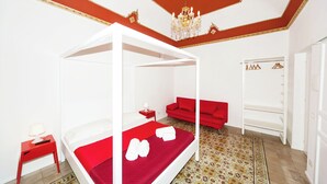 A room with a four-poster bed, a red sofa, a wardrobe, and a patterned rug. - Visitsicilia Donn'Anna 2 (Castellammare del Golfo)
