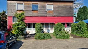 A two-story building with a red awning and a wooden facade. - Charysma: Aurum Suite | modern & elegant design | parking lot | terrace (Hameln)
