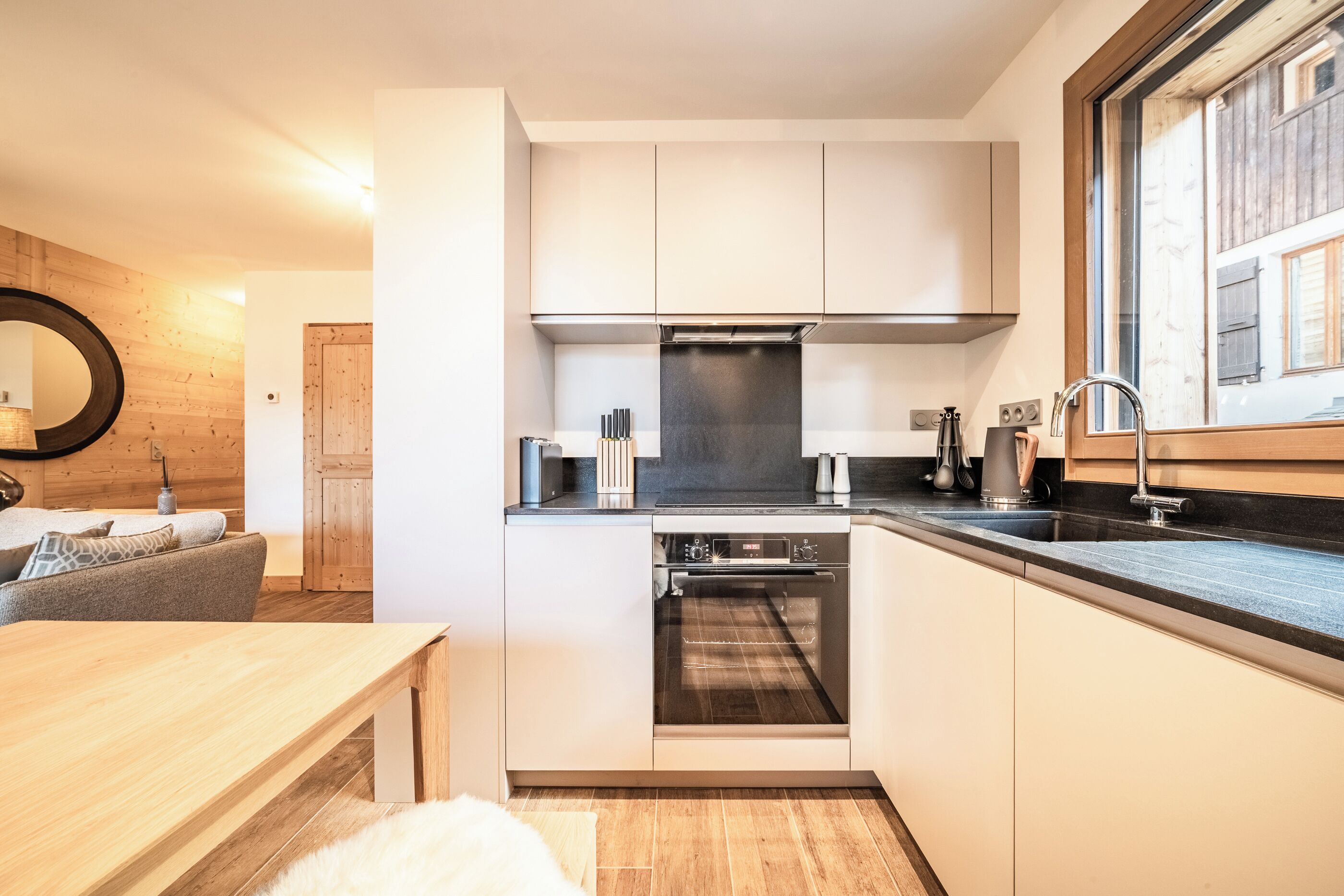 A compact kitchen with white cabinets, a built-in oven, and a window providing natural light.