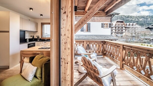 Een houten terras met een eethoek en uitzicht op een bergresort.