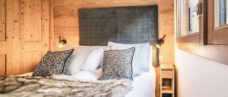 Un dormitorio con paneles de madera, una cama, almohadas y una mesita de noche.