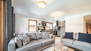 A modern living room with two sofas, a coffee table, and a kitchen in the background. - Fyndor - Apartment located in center of Morzine (Morzine)