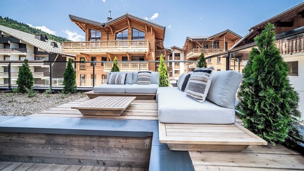 A wooden chalet with a balcony, a wooden deck, and a sofa with cushions. - Fyndor - Apartment located in center of Morzine (Morzine)