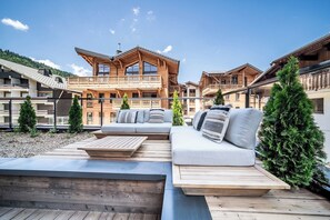 Un chalet de madera con balcón, terraza de madera y sofá con cojines.