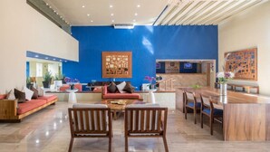 Un vestíbulo amplio con una pared azul de acento, un mostrador de recepción y zonas de estar.