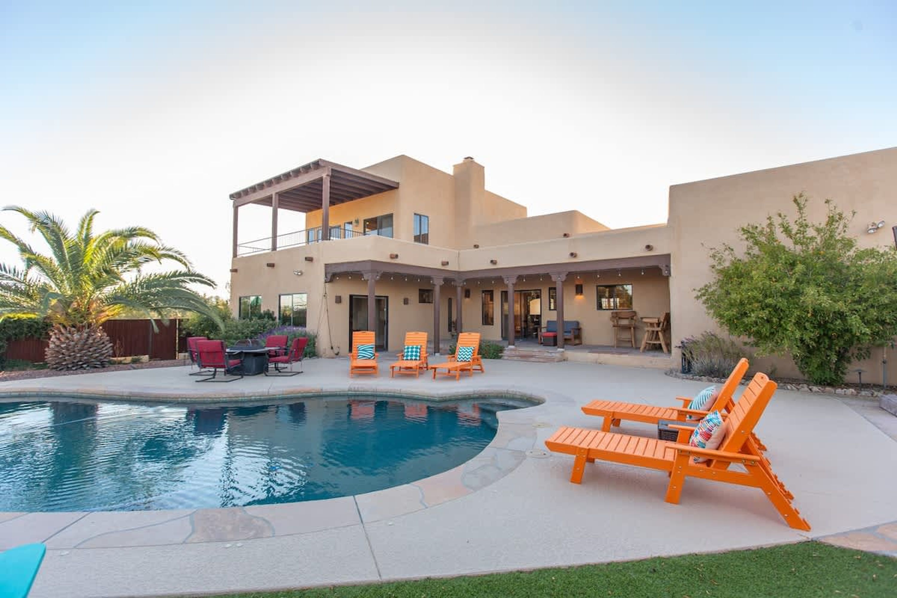 Une maison à deux étages avec une piscine, un espace salon extérieur et une terrasse couverte.