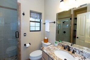A bathroom with a glass shower enclosure, a toilet, a sink with a marble countertop, and a mirror. - Spectacular Views Heated Pool Outdoor BBQ (Tucson)