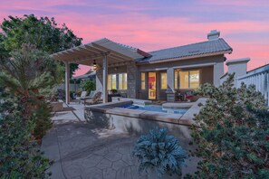 Ein modernes Haus mit überdachter Terrasse, Swimmingpool und gepflegtem Garten.