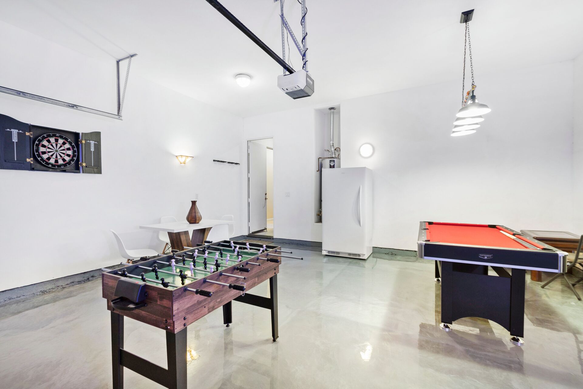 Una habitación amplia con mesa de futbolín, mesa de billar y dardos.