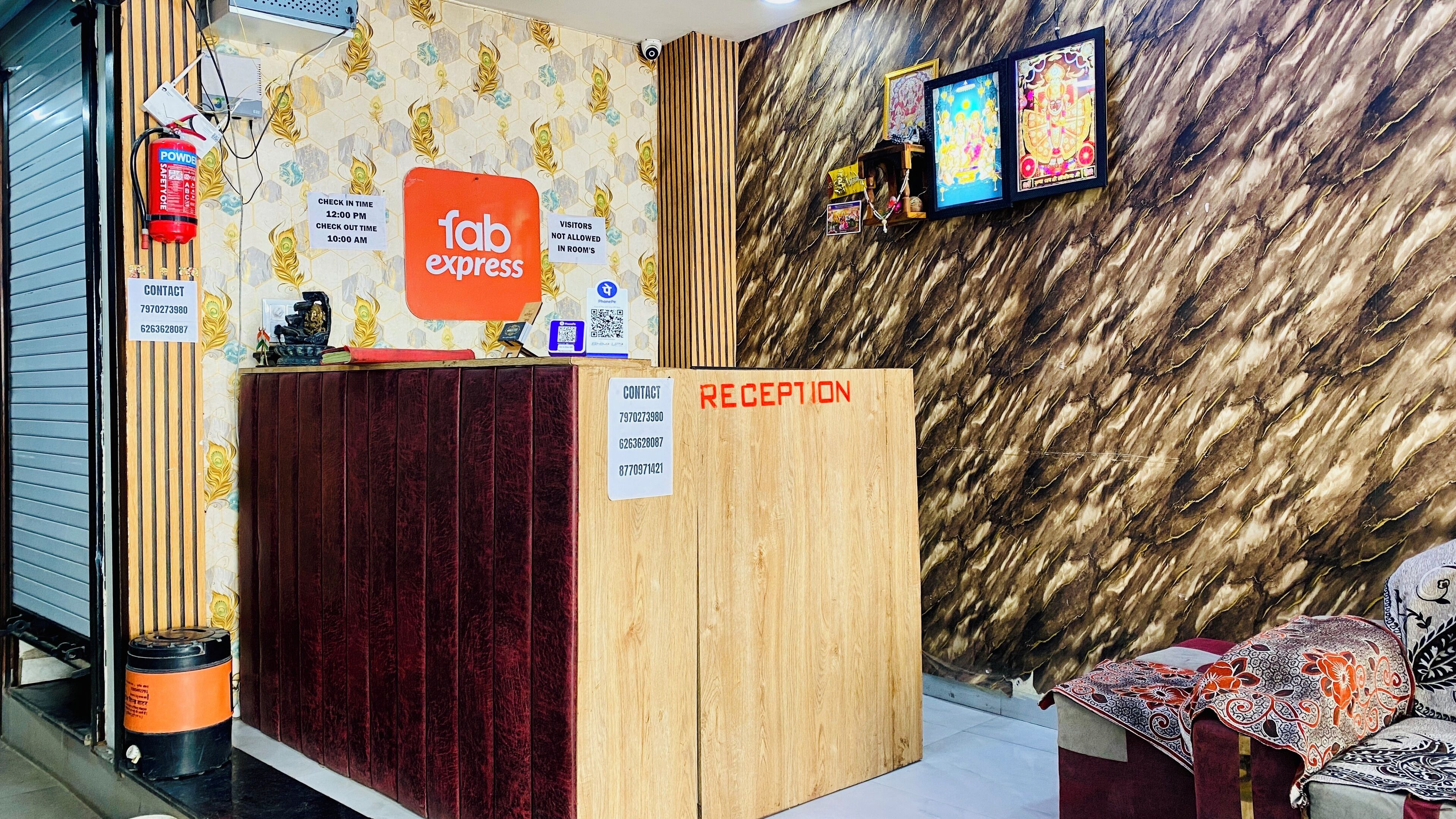 A reception desk with a 'Fab Express' sign, a 'Reception' sign, and a wall with framed pictures.
