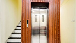 An elevator with a wooden panel design, a control panel, and a metal door. - Hotel Dev Shree (Indore)