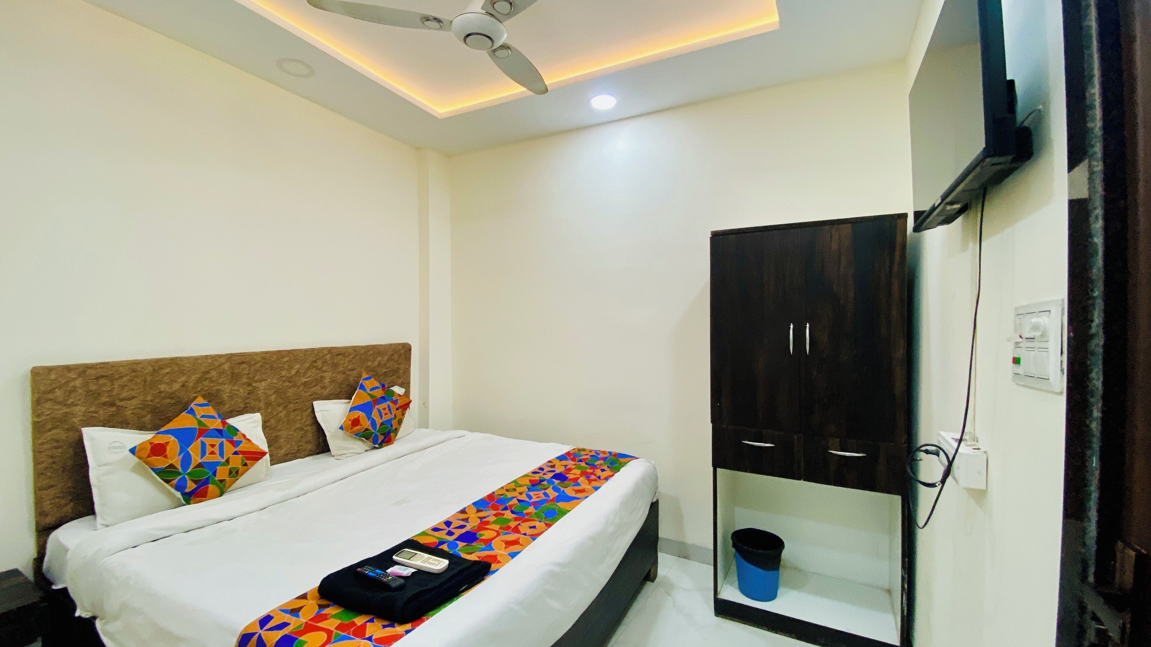 Ein Hotelzimmer mit Bett, Deckenventilator, Kleiderschrank und Fernseher.