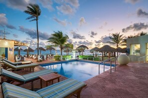 Un espace piscine comprenant des chaises longues, une piscine et des parasols.