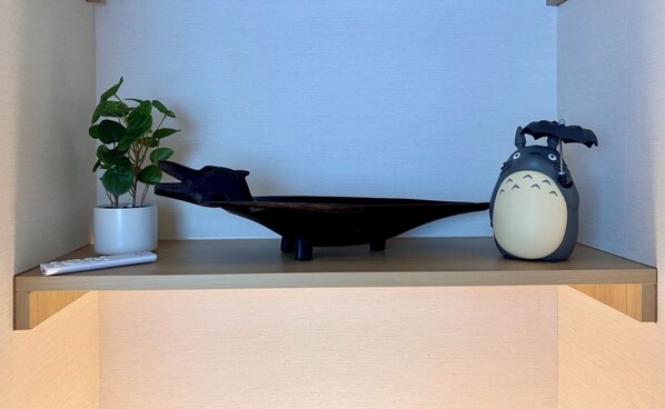 A shelf with a potted plant, a black object, a remote control, and a clock.