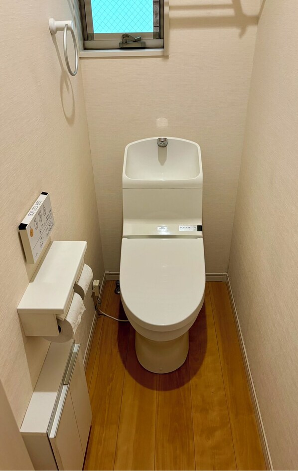 Un baño pequeño con inodoro, lavamanos y ventana sobre el inodoro.