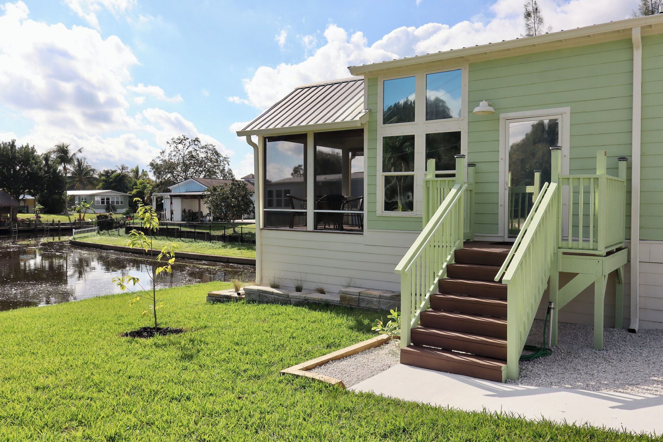 A green house with a porch and a small garden.