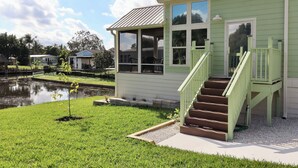 Ein grünes Haus mit einer Veranda und einem kleinen Garten.