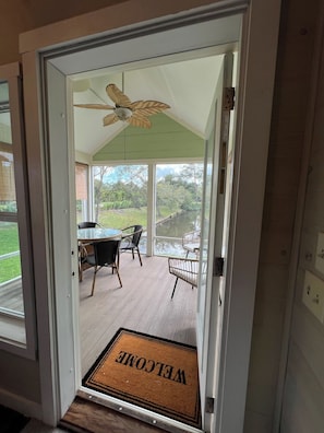 Eine überdachte Terrasse mit Tisch und Stühlen, einer Fußmatte und einem Deckenventilator.