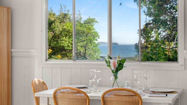 A dining area with a table set for four, overlooking a scenic view of trees and the sea. - Surfrider Studio - Pet Friendly - 50m to Beach - Book 3 Nights, Pay for 2 until 24 September 2026 (Culburra Beach)