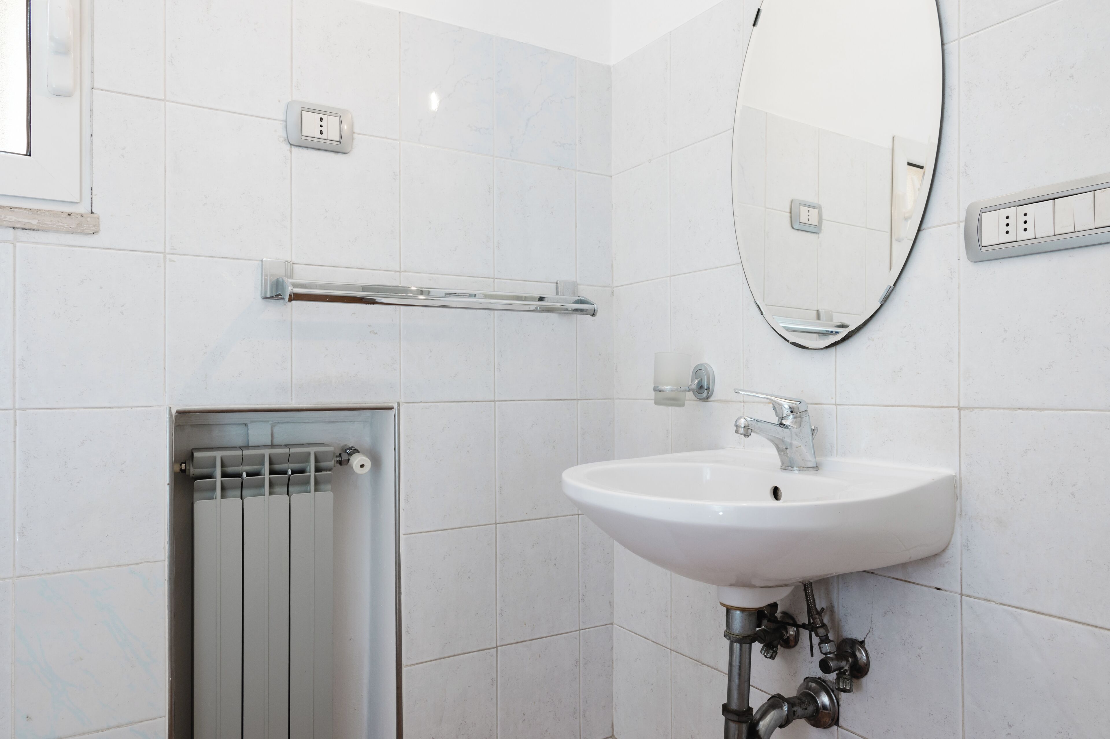 Un baño moderno con un lavamanos blanco, un espejo y un perchero para toallas.