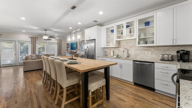 A modern kitchen with white cabinets, a dining table, and a built-in oven.