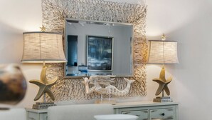 A dining area with a table set for two, a decorative mirror, and two lamps with starfish decorations.