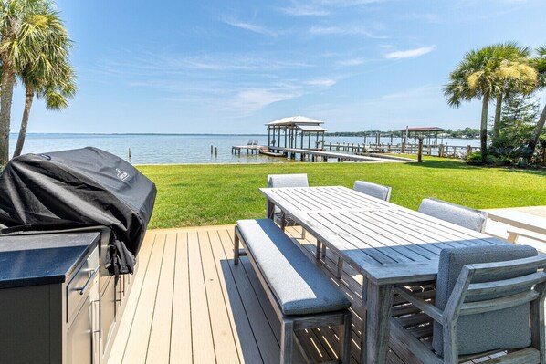 A deck with a grill, a table, and chairs, overlooking a marina with docks and boats. - Hidden Gem, New Patio, Private Dock (Santa Rosa Beach)