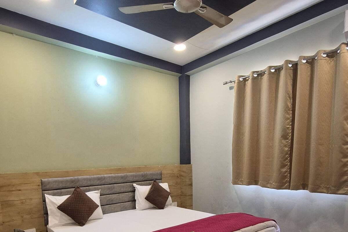 A neatly arranged bedroom with a wooden bed frame, a ceiling fan, and a window with curtains.