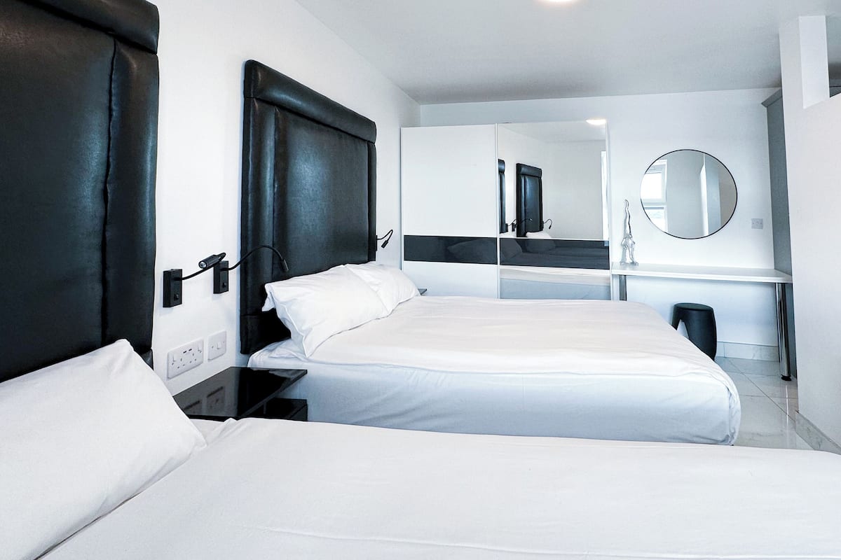 Een hotelkamer met twee bedden, een bureau, een spiegel en een prullenbak.