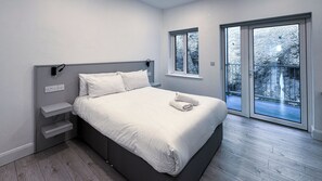 Une chambre à coucher moderne, avec un lit, des tables de chevet, une fenêtre et une vue sur l  ’extérieur.