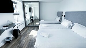 Una habitación de hotel moderna con una cama grande, una cama más pequeña, un escritorio y un televisor.