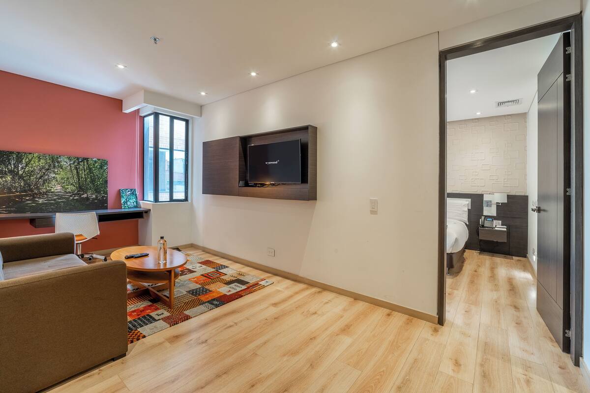 Una sala de estar moderna con un televisor de pantalla plana, un sofá, una mesa de centro y una alfombra estampada.
