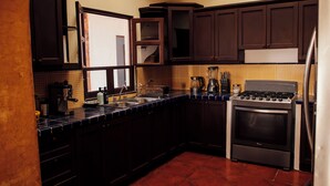 Una cocina con armarios de madera oscura, estufa de acero inoxidable y salpicadero de azulejos.