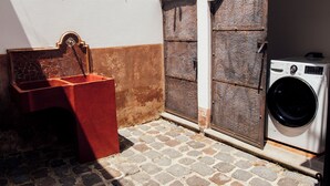 Un área de lavandería con lavadora, un lavabo rojo y dos puertas grandes.
