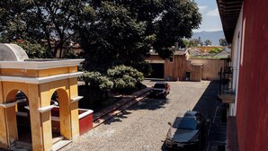 Una calle adoquinada con coches aparcados y un edificio con arcos.