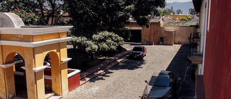 A cobblestone street with parked cars and a building with arches.