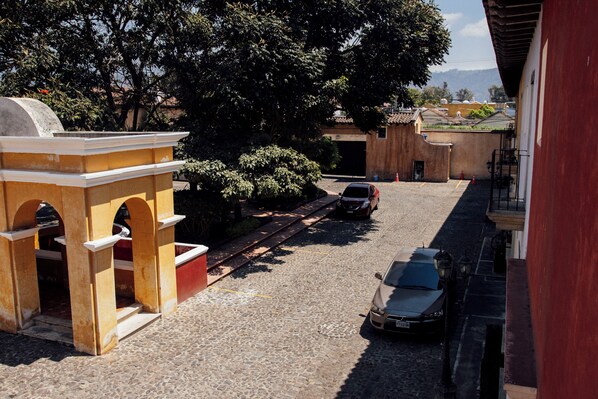 A cobblestone street with parked cars and a building with arches.