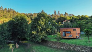 A small wooden cabin with a red roof, surrounded by lush greenery and trees. - Sistelo - Sleeps4 - Naturalpool- Garden - Parking (Arcos de Valdevez)