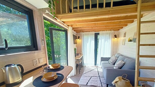 A cozy cabin interior with a wooden dining table, a sofa, and a staircase. - Sistelo - Sleeps4 - Naturalpool- Garden - Parking (Arcos de Valdevez)